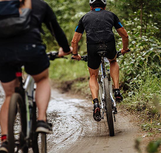 class-pic-2 two people riding bikes down a muddy trail